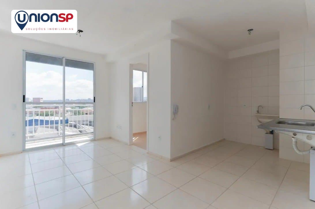 Sala de estar integrada com a área da cozinha, com piso claro e porta para varanda.